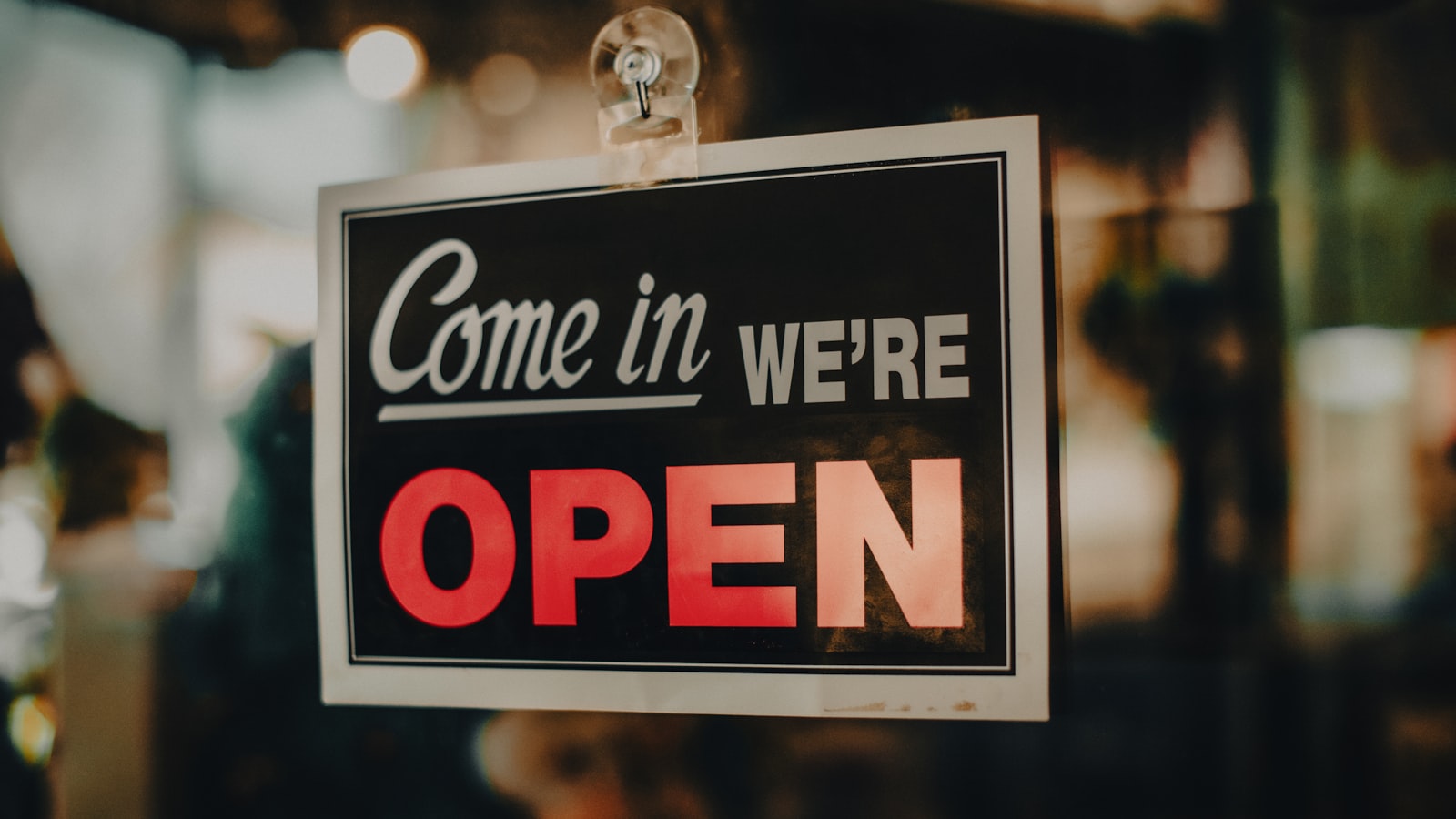 A 'Come in, we're open' sign in English hanging on a restaurant door