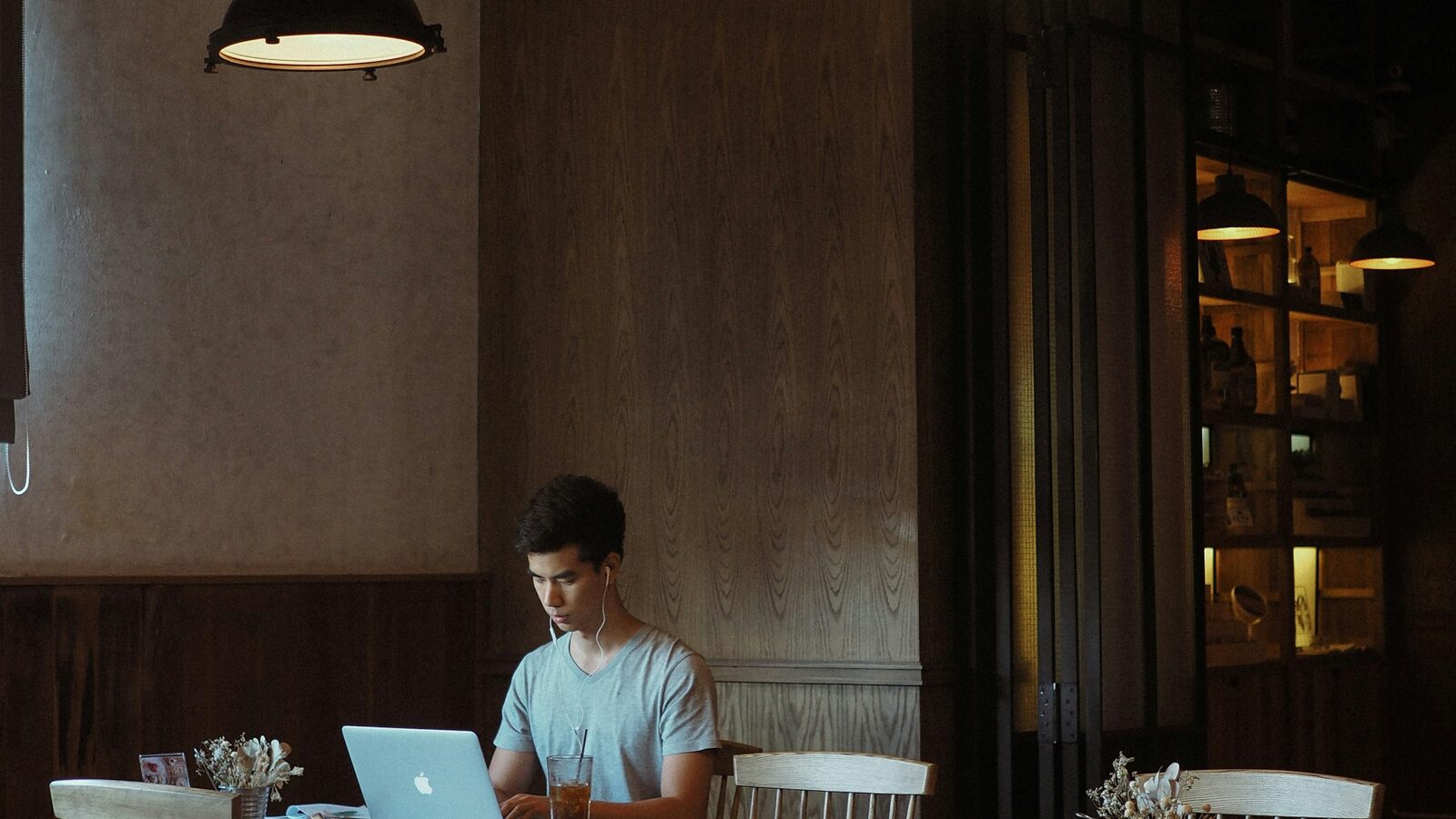 A restaurant owner working on a laptop at a table inside a quiet restaurant