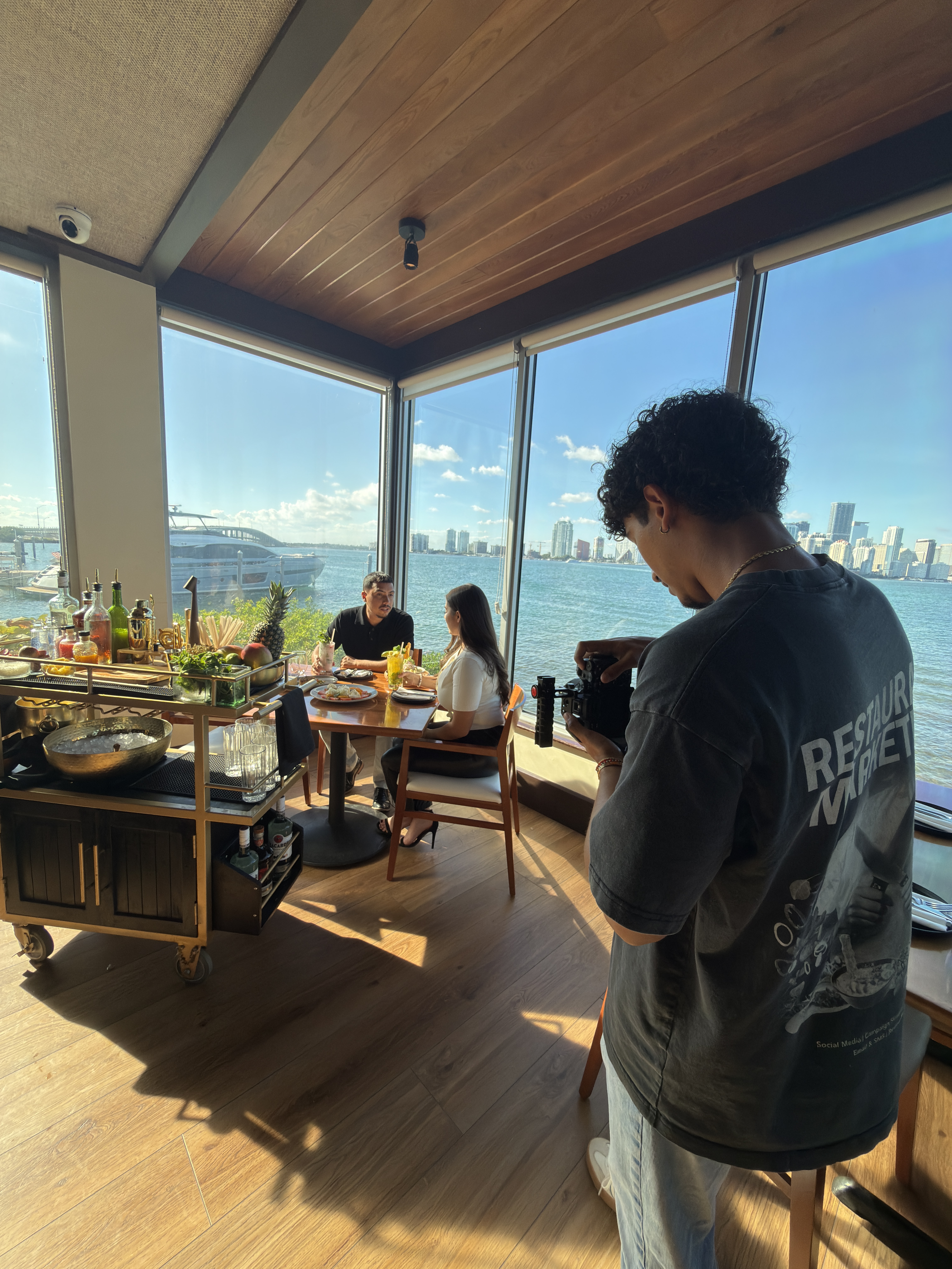 Button Up Media videographer filming a couple dining at a Miami waterfront restaurant
